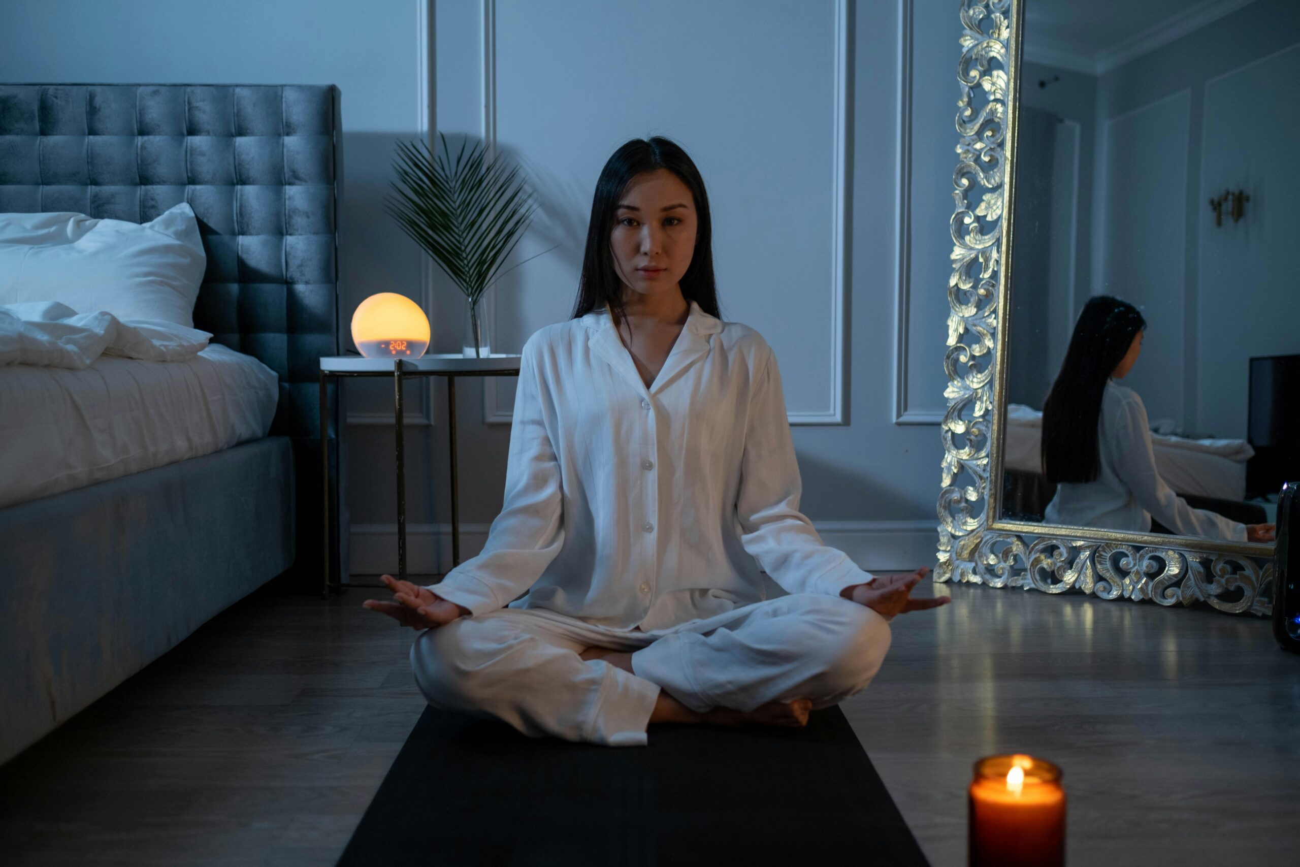 Person meditating in serene bedroom setting.