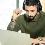 Person working on laptop with headphones.