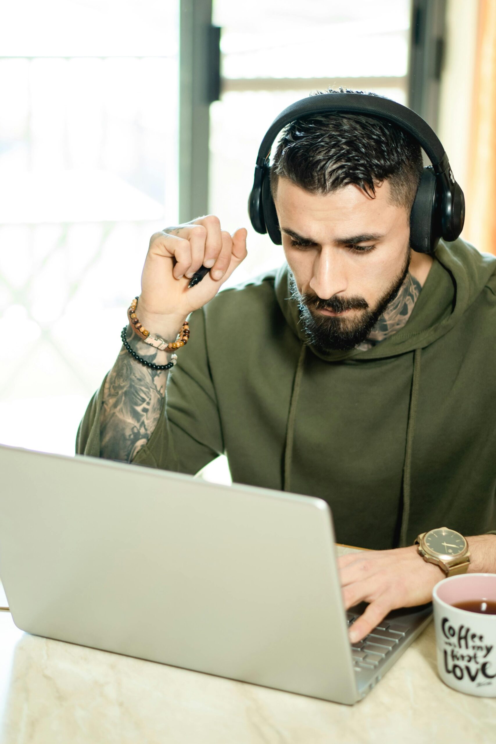 Person working on laptop with headphones.