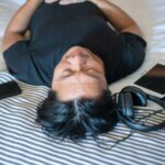 Person resting with headphones and devices.