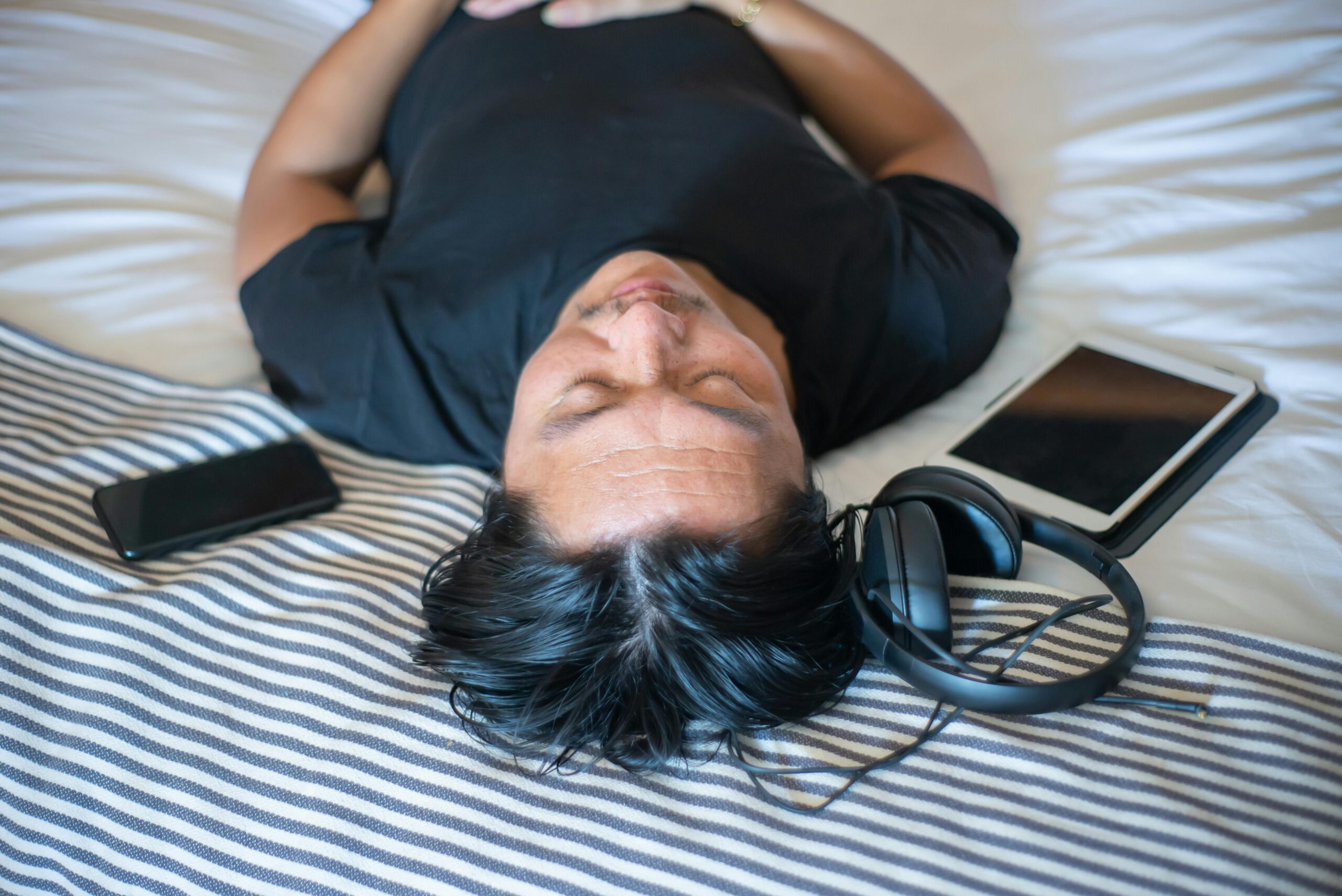 Person resting with headphones and devices.